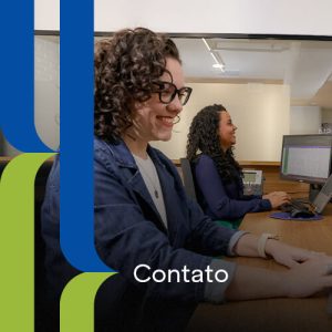 mesa de escritório em ambiente coorporativo com duas mulhers trabalhando felizes em computadores dektop