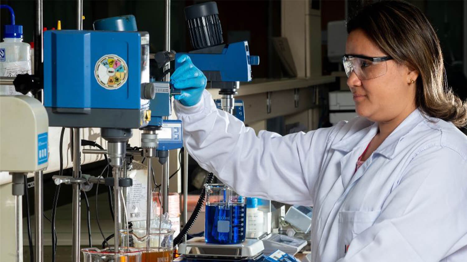 Colaboradora da ICONIC em um laboratório químico, utilizando equipamentos de proteção individual.